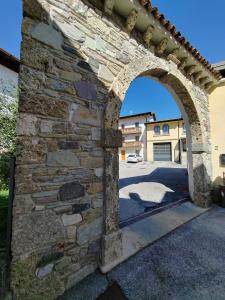 an archway in a stone wall with a driveway at Appartamento Peç in Sùtrio