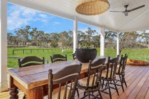 a wooden table and chairs on a porch with a view of a field at Wembley Cottage, Southern Highlands in Berrima +24 photos