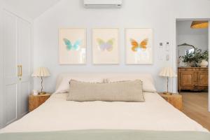 - une chambre avec un lit blanc aux papillons sur le mur dans l'établissement Wembley Cottage, Southern Highlands, à Berrima