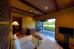 uma sala de estar com um sofá e uma televisão em Ryokan Konomama em Minami Aso