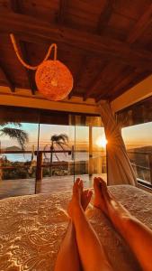a person laying on a bed with their feet on it at Casa do Morro in Praia do Rosa +8 photos