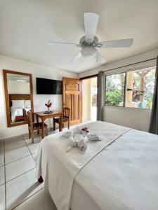 a bedroom with a white bed with a ceiling fan at Akwaba Lodge in The Gap