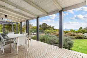 un patio con mesa y sillas en una terraza de madera en Honeysuckle House, en Shoreham