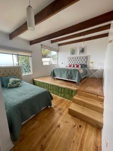 two beds in a room with wooden floors and windows at Hostal Napoli in Valparaíso