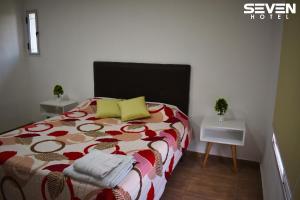 um quarto com uma cama com um edredão colorido e 2 mesas em Seven Hotel - Juana Koslay San Luis em Juana Koslay 
