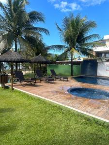 a patio with chairs and a swimming pool with palm trees at Village ITACIMIRIM in Camaçari