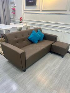 a brown couch with two blue pillows on it at Ali Homestay Sungai Petani in Sungai Petani