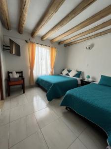 1 dormitorio con 2 camas y edredón verde en Tres habitaciones en la cabaña Quinta Buenos Aires, en Villa de Leyva