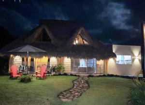 - une maison de nuit avec des chaises et un parasol dans l'établissement Cabana para 6 con Alberca a solo 3 min de la Playa de Chacala Nayarit, à Chacala