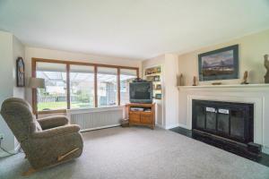 a living room with a fireplace and a chair and a television at Surfers Cove in Seaside