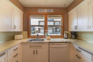a kitchen with white cabinets and a sink and a window at Surfers Cove in Seaside +16 photos