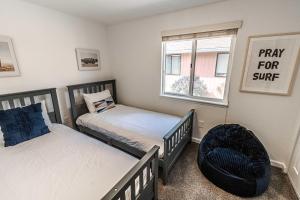 a bedroom with two beds and a chair and a window at Cozy Cove Cottage in Seaside