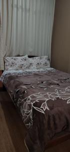 Una cama con un edredón marrón con flores. en Hostal El Ángel, en Chachapoyas