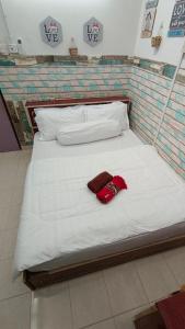 ein weißes Bett mit einem roten Hut drauf. in der Unterkunft Teres luas & selesa, dekat shopping mall, UMT in Kuala Terengganu