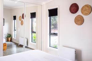 a bedroom with white walls and windows at Whale Watcher 2 in Coles Bay