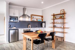 a kitchen with a wooden table and black chairs at Whale Watcher 2 in Coles Bay