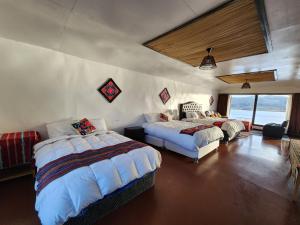 um quarto com 2 camas e uma grande janela em Titicaca island lodge peru em Puno