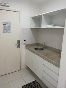 - une cuisine blanche avec un évier et une porte dans l'établissement FLAT FUSION, à Brasilia