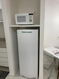 um micro-ondas em cima de um frigorífico numa cozinha em FLAT FUSION em Brasília
