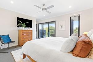 a white bedroom with a large bed and a chair at Cape Retreat in Cape Schanck