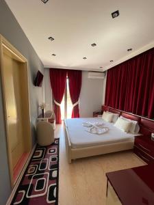 een slaapkamer met een groot bed met rode gordijnen bij Hotel Selfo in Gjirokastër