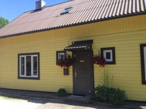 een geel huis met een zwarte deur en bloemen bij Embrace Apartments in Pärnu