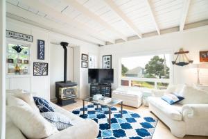 a living room with white furniture and a fireplace at Coral Cottage in Depoe Bay