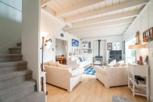 a living room with white furniture and a staircase at Coral Cottage in Depoe Bay