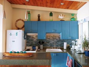 a kitchen with blue cabinets and a white refrigerator at Driftwood Cottage in Seal Rock