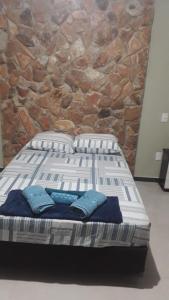 a bed with two pillows in front of a stone wall at Chalés Bela Vista in Serra Negra