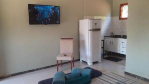 a kitchen with a refrigerator and a chair at Chalé Bela Vista in Serra Negra