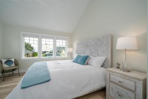 a white bedroom with a bed and a window at Hydrangea House in Seaside