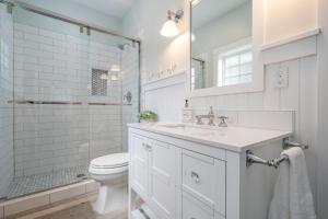 a white bathroom with a toilet and a sink at Hydrangea House in Seaside
