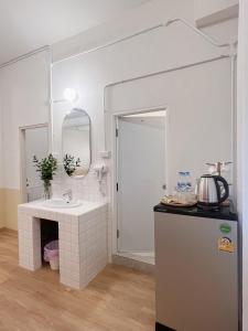 a kitchen with a sink and a mirror and a refrigerator at La Moon House in Salaya