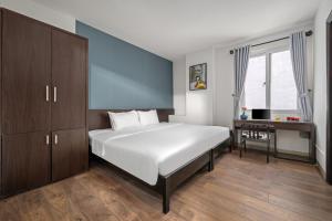 1 dormitorio con 1 cama blanca grande y escritorio en Gold Time Hotel Da Nang, en Da Nang