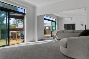 a living room with a couch and sliding glass doors at Recline on Leo in Waihi Beach