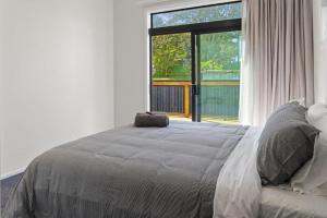 a bedroom with a bed and a large window at Recline on Leo in Waihi Beach