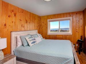 a bedroom with wooden walls and a bed with a window at Estuary Cottage in Seaside
