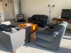 uma sala de estar com três sofás e uma televisão em 6 Dumblane Way em Hanmer Springs