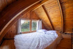 uma cama num quarto de madeira com uma janela em Chalé Alpino em Apiúna