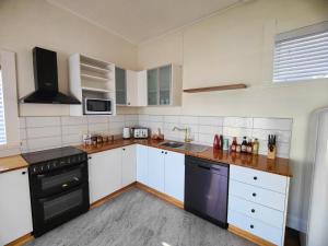 a kitchen with white cabinets and black appliances at Three Bedrooms Hermay Cottage in Invermay +13 photos