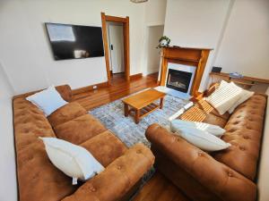 a living room with a brown couch and a fireplace at Three Bedrooms Hermay Cottage in Invermay