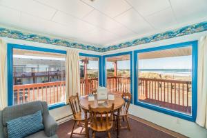 a dining room with a table and chairs and windows at Getaway Oceanfront Lodging in Rockaway Beach