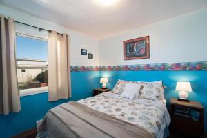 a blue bedroom with a bed and a window at Getaway Oceanfront Lodging in Rockaway Beach