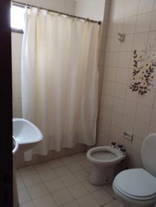 a bathroom with a toilet and a shower curtain at Bravard suites in Bahía Blanca