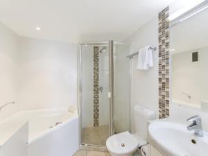 a white bathroom with a shower and a toilet and a sink at Coolum Caprice in Coolum Beach