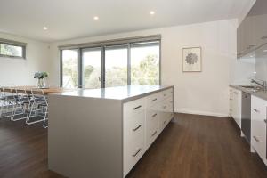 a kitchen with white cabinets and a large island at Rolling Waves in Pt Leo in Shoreham