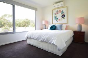 a white bedroom with a bed and a large window at Rolling Waves in Pt Leo in Shoreham