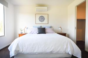 a white bedroom with a large white bed with pillows at Rolling Waves in Pt Leo in Shoreham