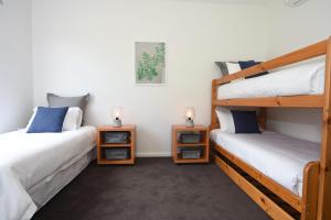 a bedroom with two bunk beds and two lamps at Rolling Waves in Pt Leo in Shoreham